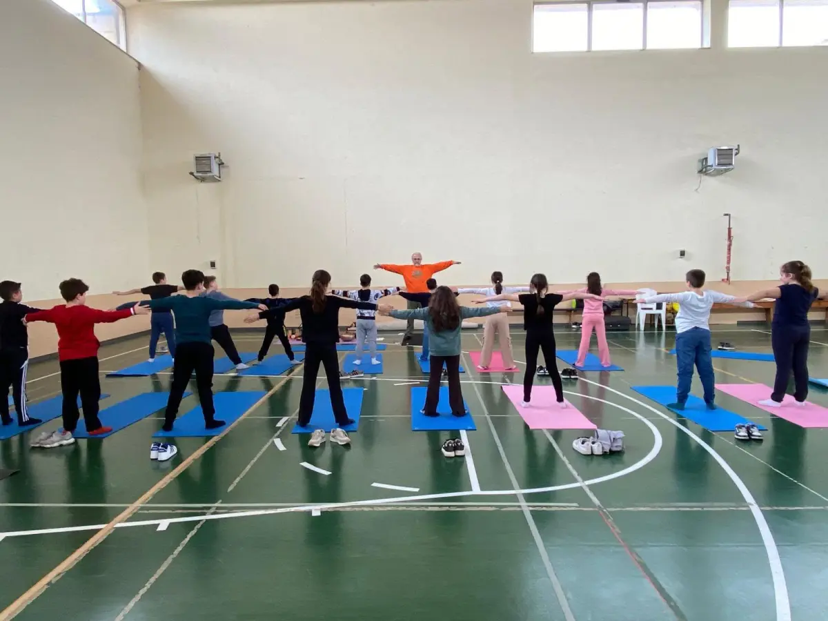 Lezione di Yoga Bimbi dell'Associazione Dharmonia: bambini in posizione della stella insieme all'istruttore